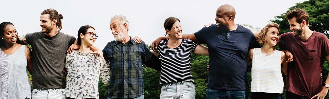 People standing in a line outside with their arms over each other.
