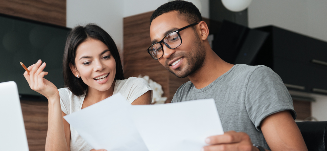 A man and woman sitting together and looking at papers.
