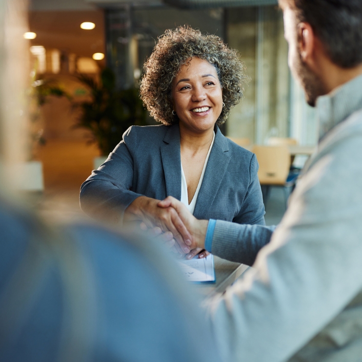 A man and woman exchanging a handshake in an office.
