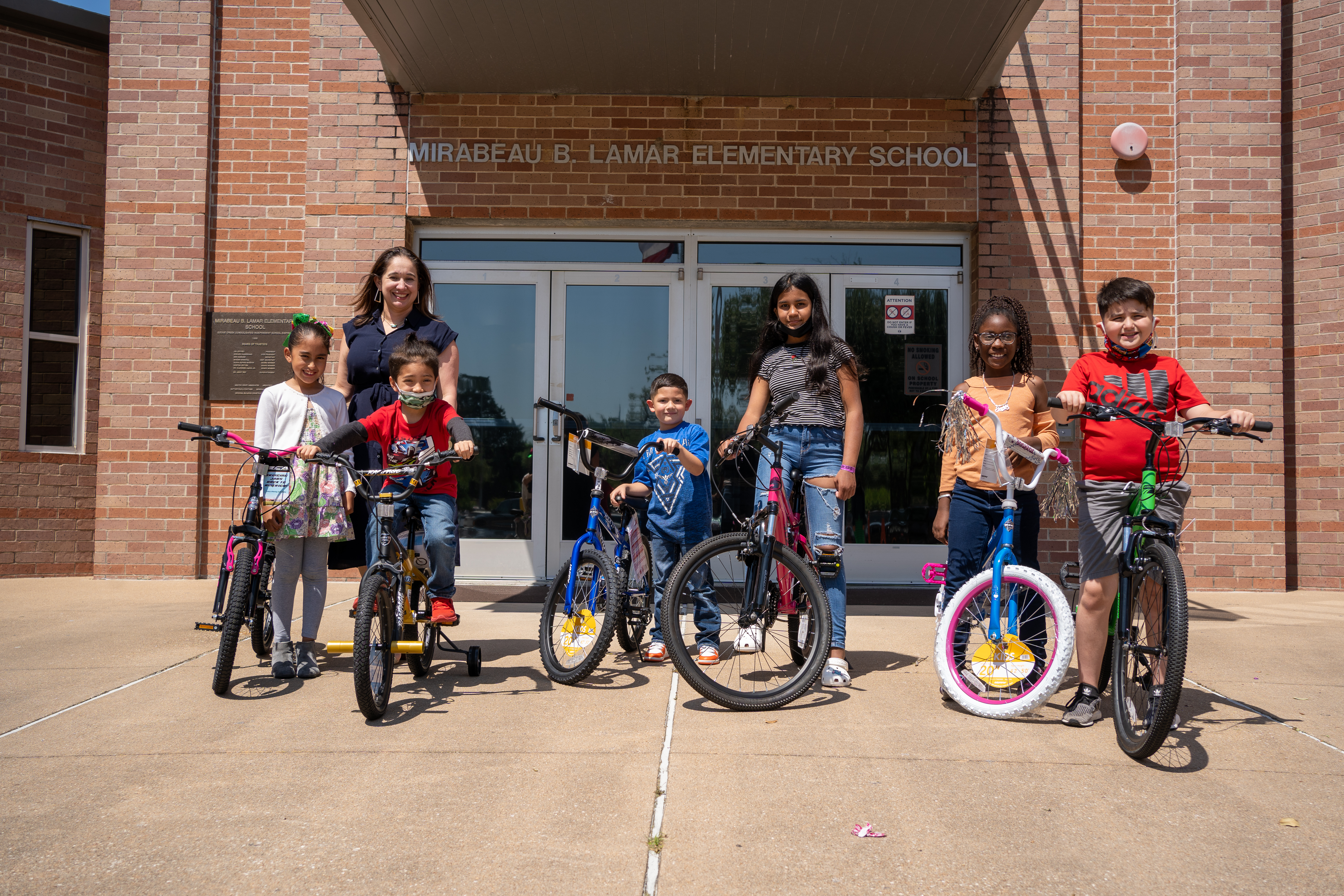 Kids and an adults standing in front of Mirabeau B. Lamar Elementary School.
