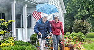 An elderly couple walking together outside of their home.
